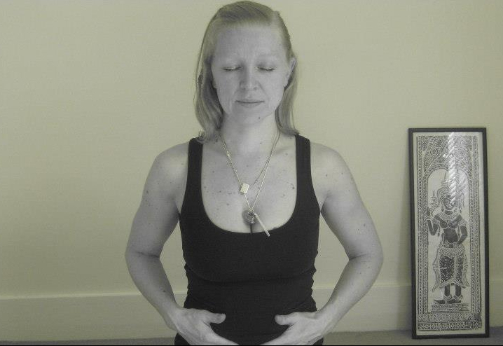 Stephanie Price standing with eyes closed and hands resting on her abdomen